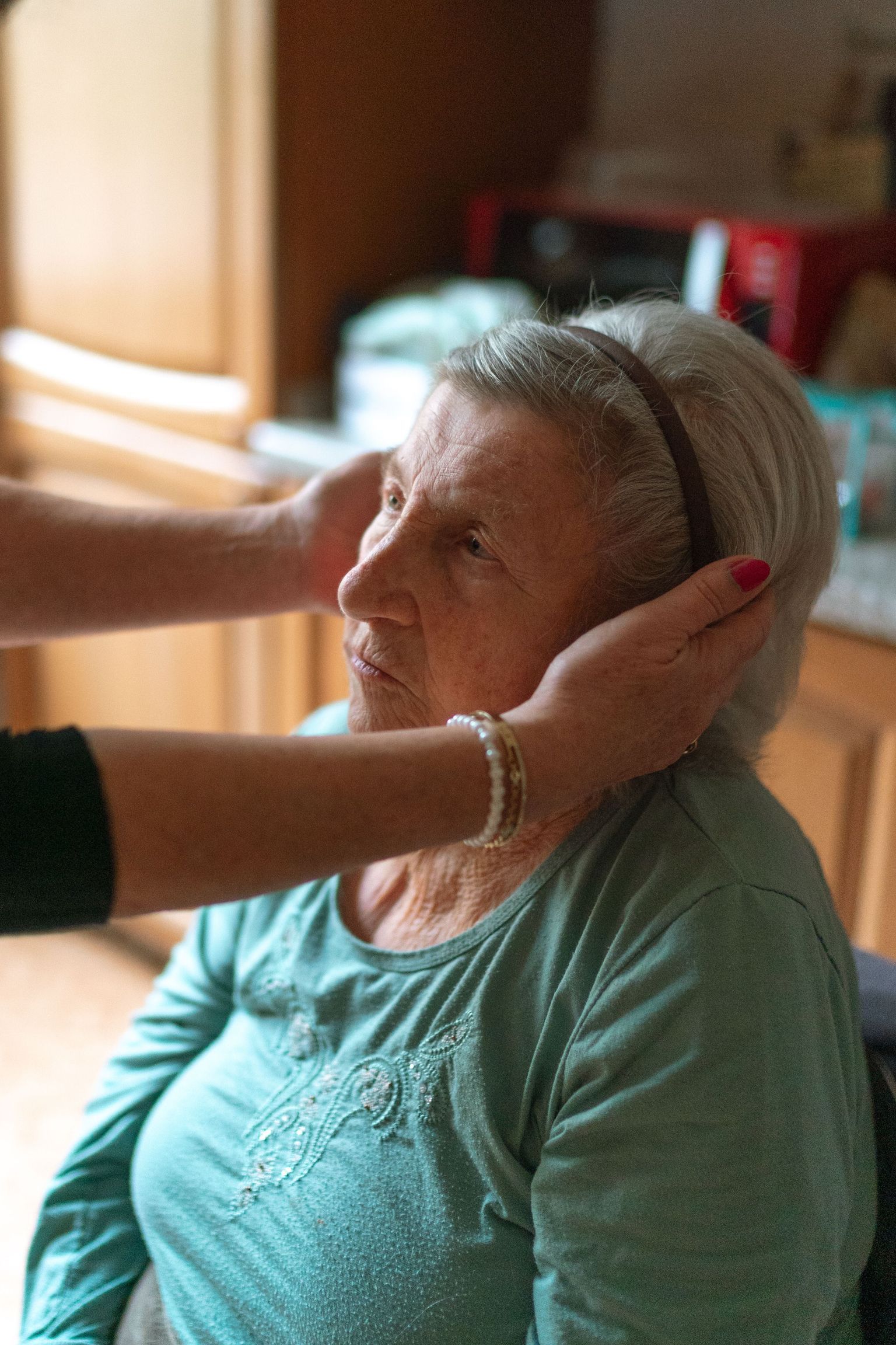 A senior woman receiving attentive home care assistance indoors, promoting comfort and support.